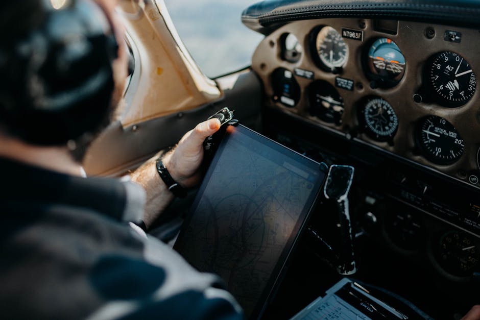 Pilot using tablet for navigation inside an airplane cockpit, showcasing aviation technology.